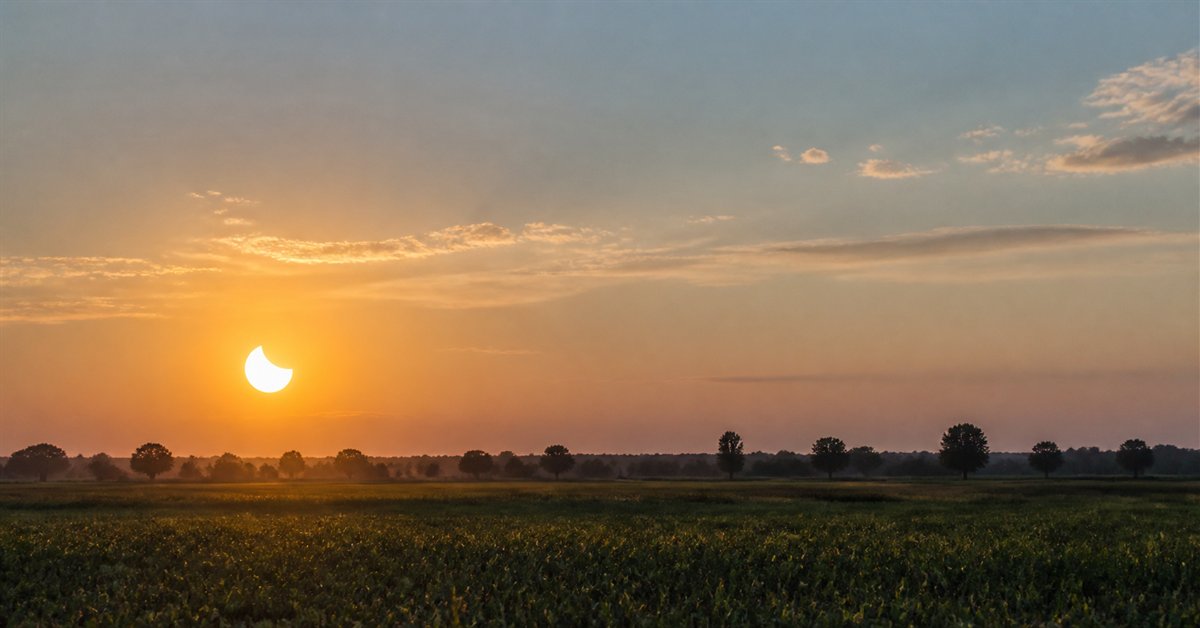 Partielle Sonnenfinsternis über freiem Feld bei Sonnenuntergang Raesfeld