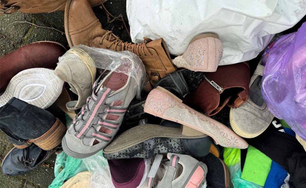 Kleidung und Müll vor dem Altkleidercontainer in Erle