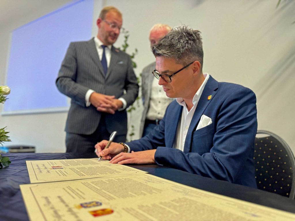 Dirk Kuhmann unterzeichnet die Urkunde zur Partnerschaft zwischen Raesfeld und Wehl.
