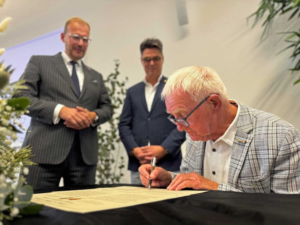 Joop Buiting unterzeichnet die Urkunde zur Partnerschaft zwischen Raesfeld und Wehl.