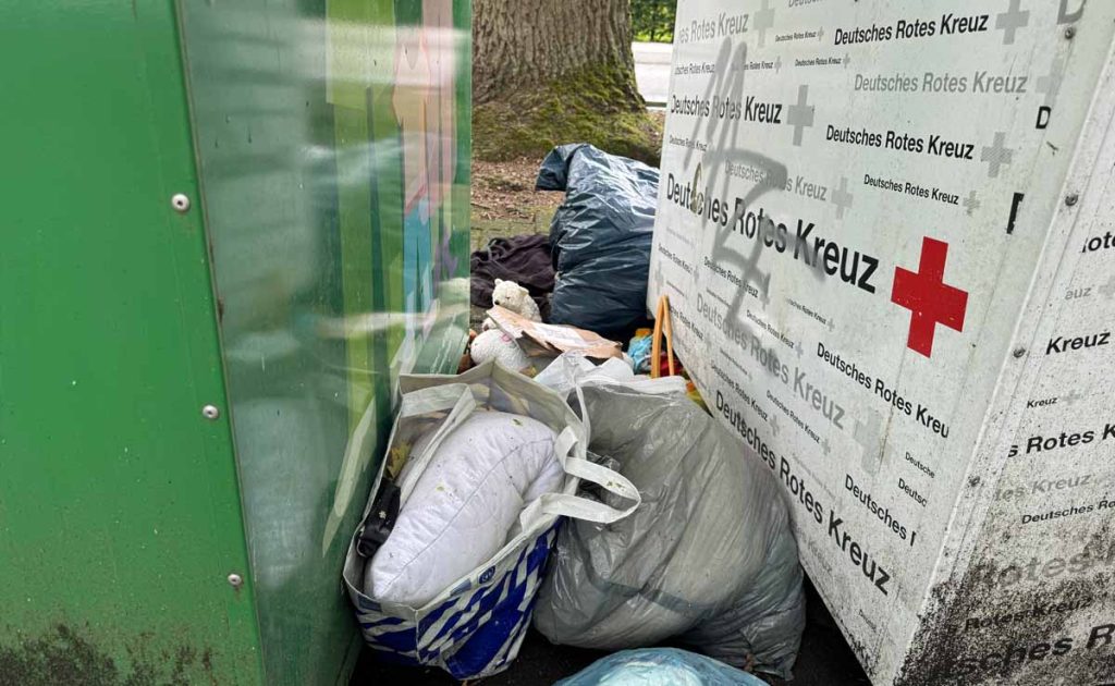 Kleidung und Müll vor dem Altkleidercontainer in Erle