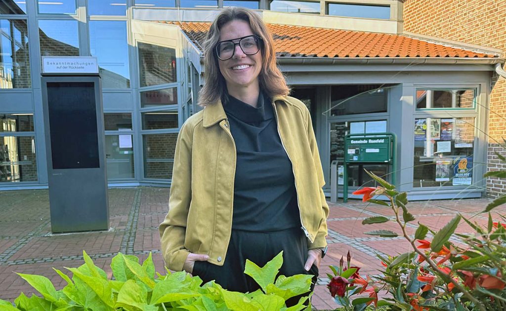Wirtschaftsförderin Sabrina Greiwe steht vor dem Rathaus Raesfeld hinter einem Blumenbeet.